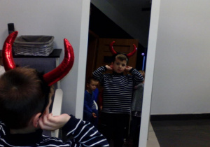 Chłopiec przymierza rekwizyt- rogi diabełka przeglądając się w lustrze.